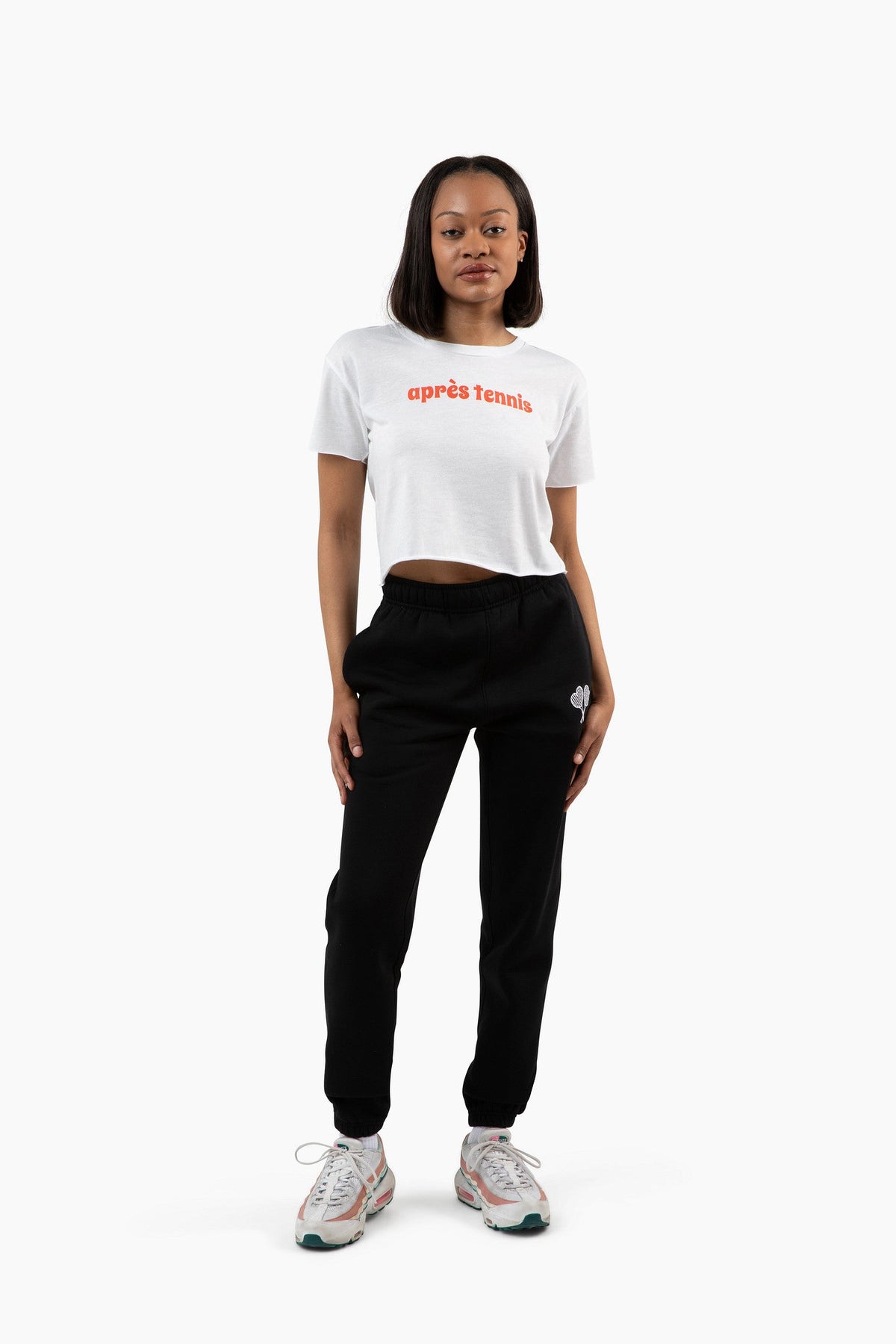 Person wearing a white cropped t-shirt with red text and black pants on a white background