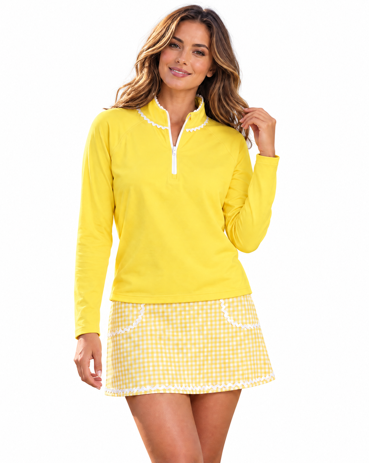 A woman modeling a bright yellow long-sleeve quarter-zip top with white trim and a matching yellow-and-white gingham mini skirt with white trim, against a plain white background.