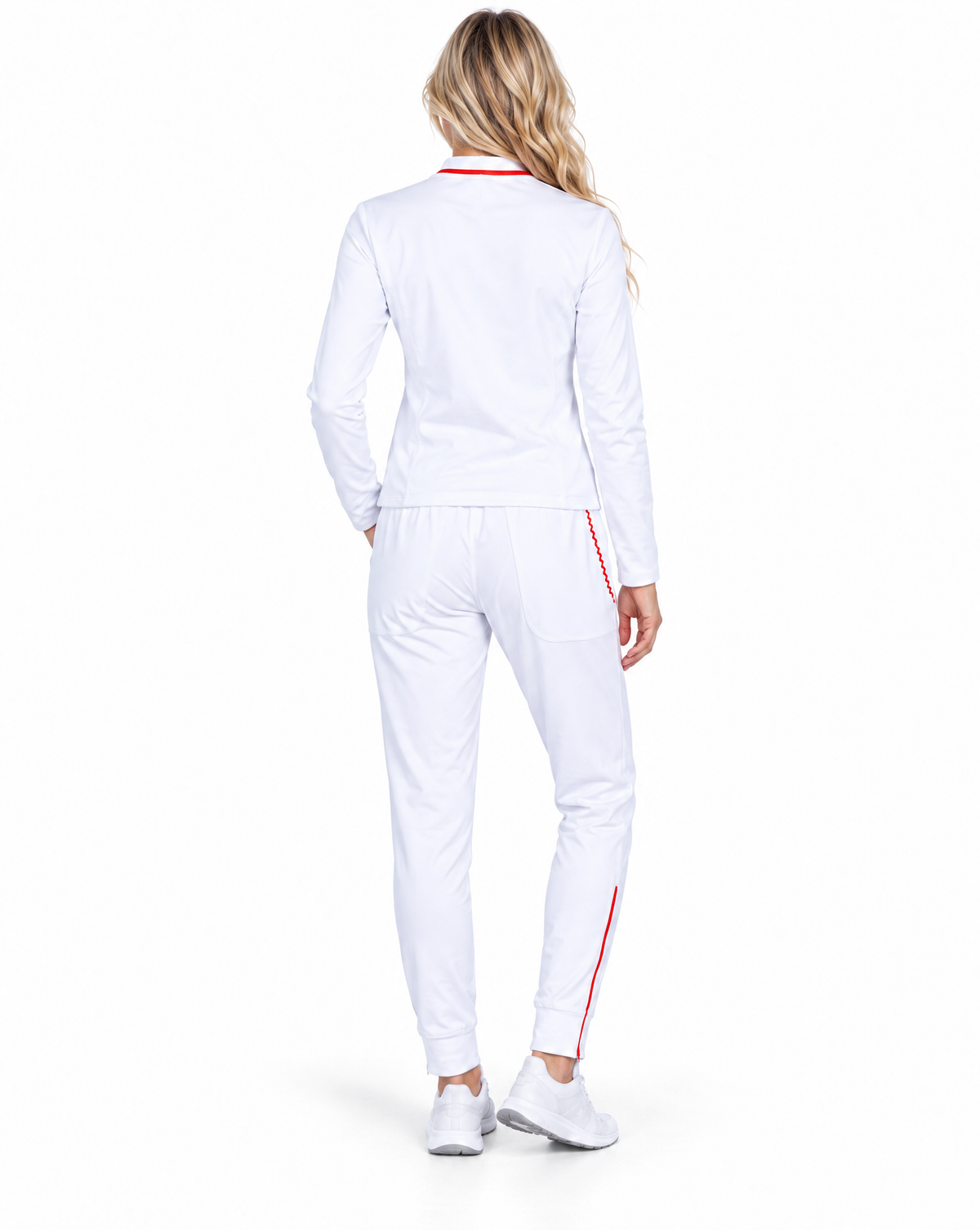 A woman viewed from behind wearing a white long-sleeve athletic jacket and matching white jogger-style pants with thin red side stripes, paired with white sneakers on a clean white studio background.