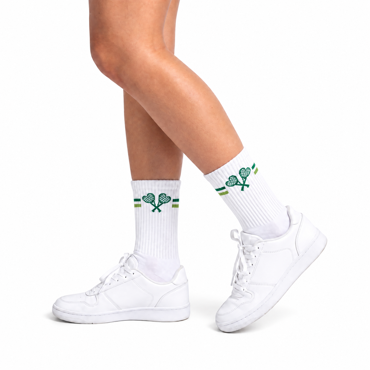 White crew socks with a green crossed-tennis-racquet and heart design, worn with white sneakers on a clean white background.