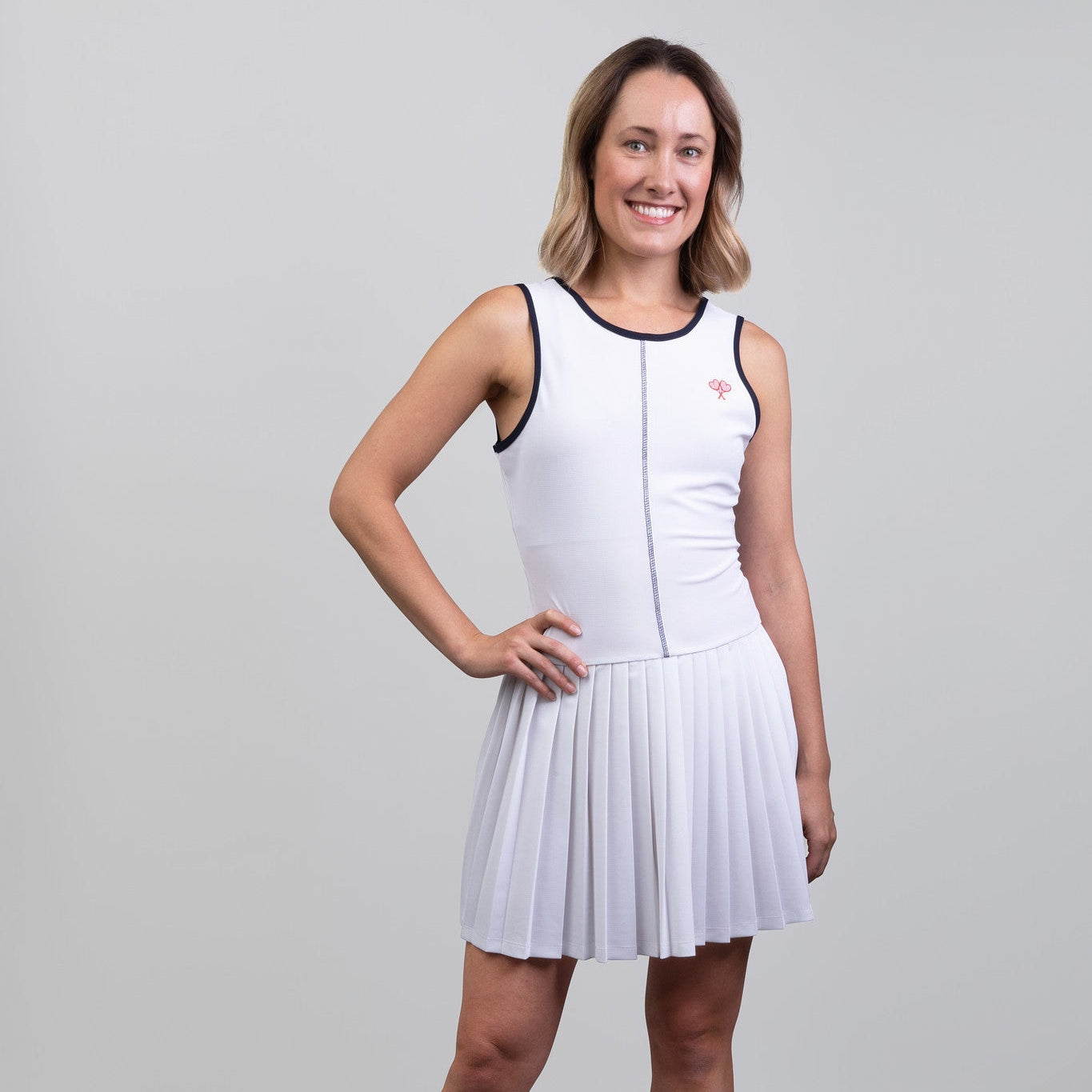 Woman wearing a white dress with navy trim on a gray background