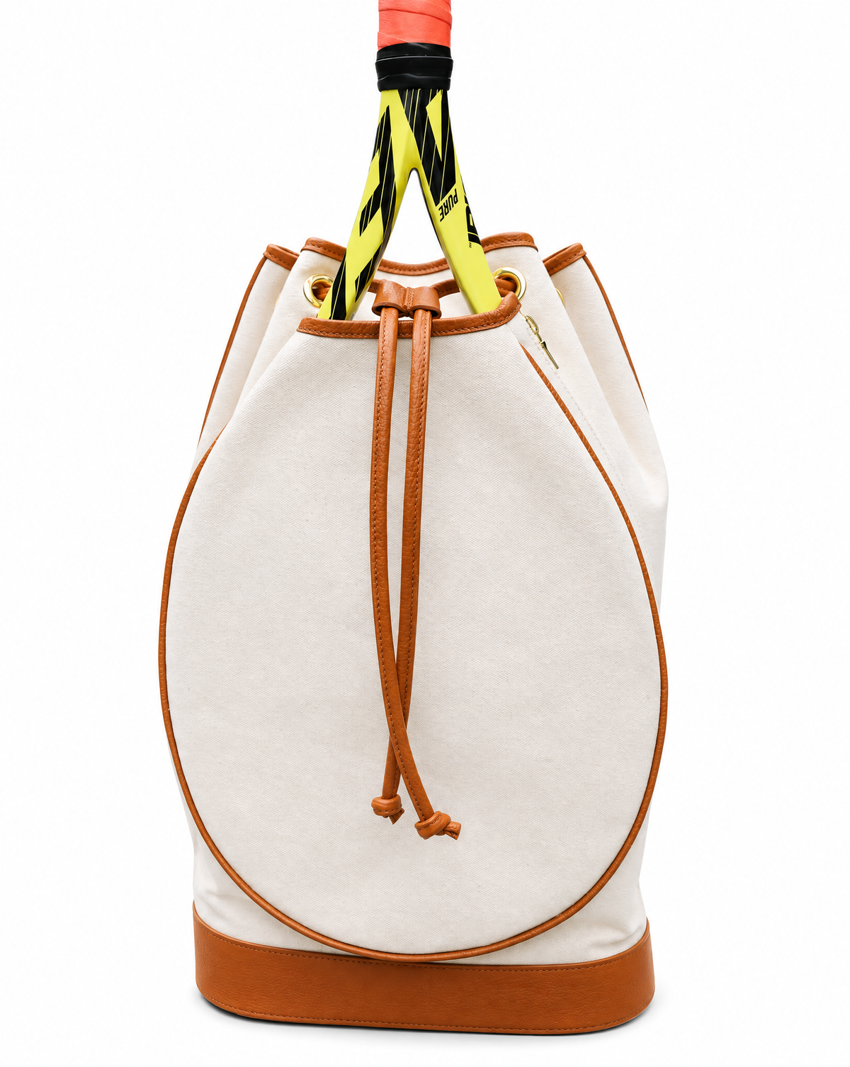 A canvas bucket bag in off-white with tan leather trim, featuring a drawstring closure and a tennis racket tucked inside, set against a plain white background.