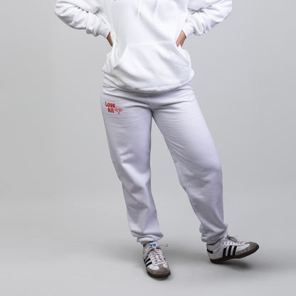 Person wearing a white hoodie and pants set with visible branding on a gray background