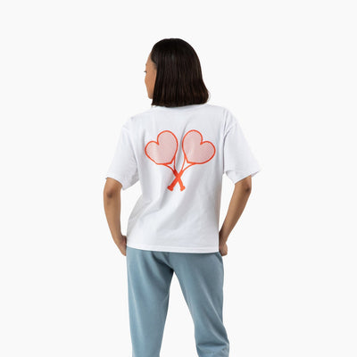 Person wearing a white t-shirt with a heart design on the back, standing against a white background.