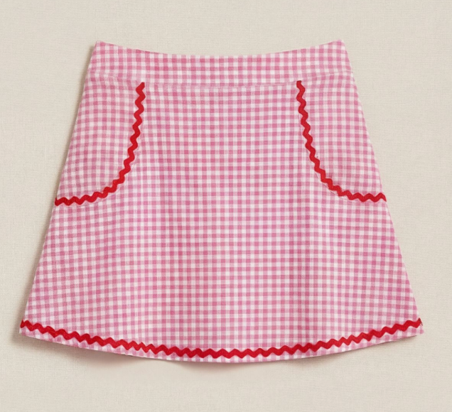 Pink gingham skirt with red trim on a beige background