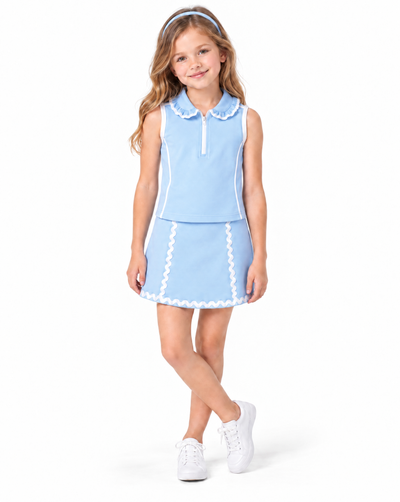 A young girl modeling a light blue sleeveless collared top and matching mini skirt set with white trim, paired with white sneakers, on a solid white background.