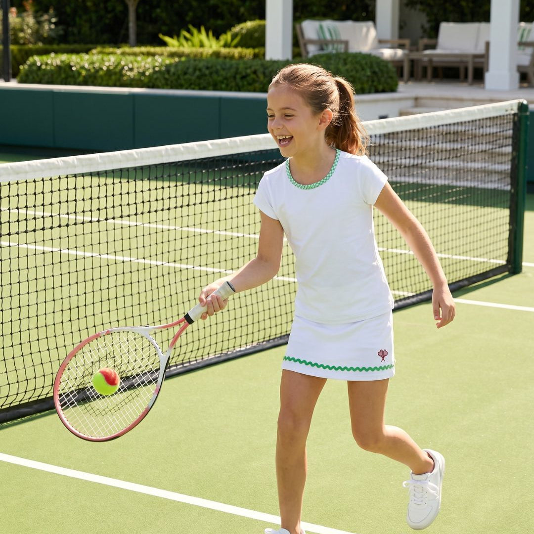 Young girl playing tennis on a court with a racket and ball.
