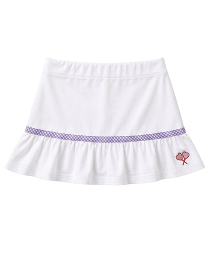A white ruffled skirt with a purple gingham pattern band around the waist and a small red embroidered heart tennis rackets crossed motif on the lower right side, shown against a plain white background.