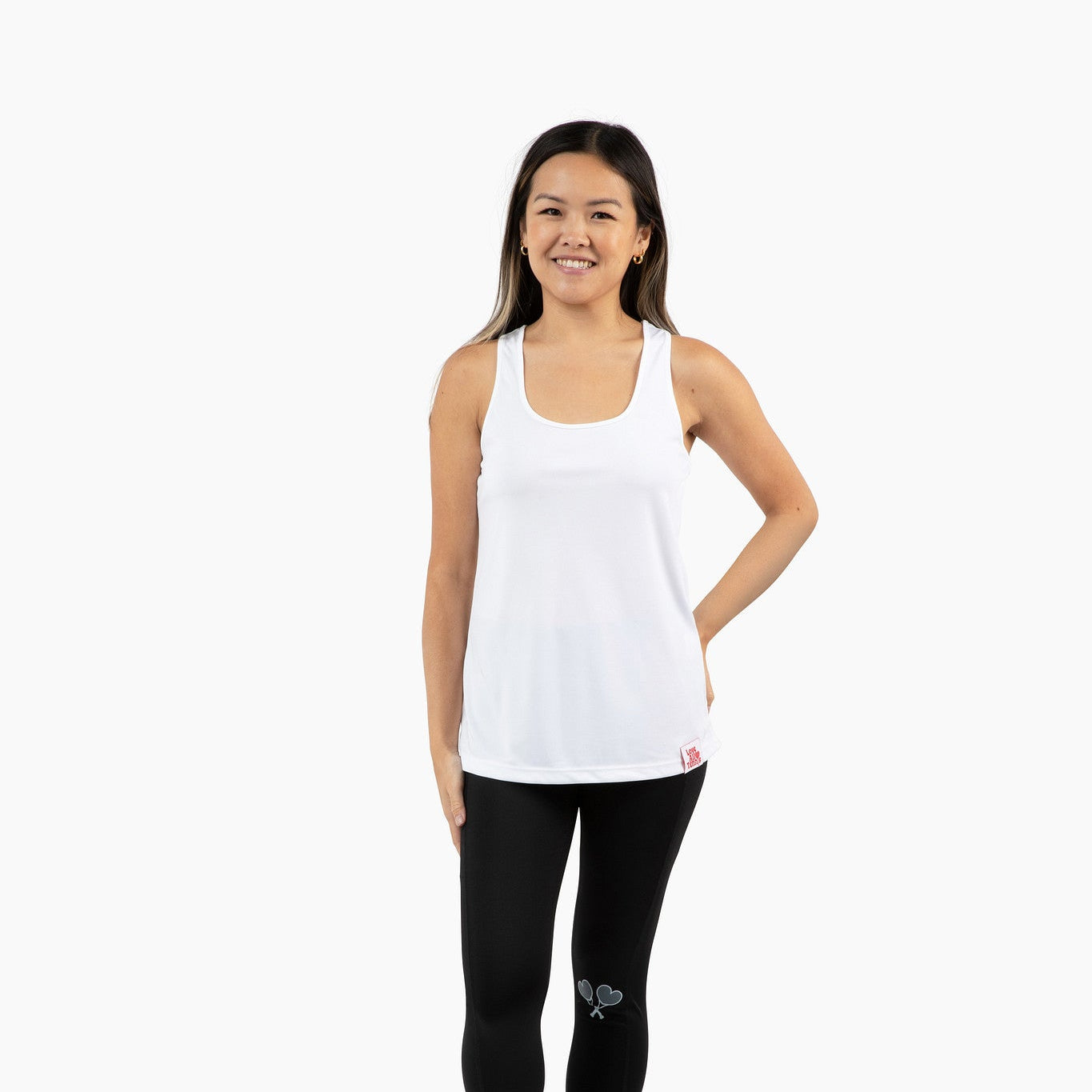 Woman wearing a white tank top and black leggings on a white background