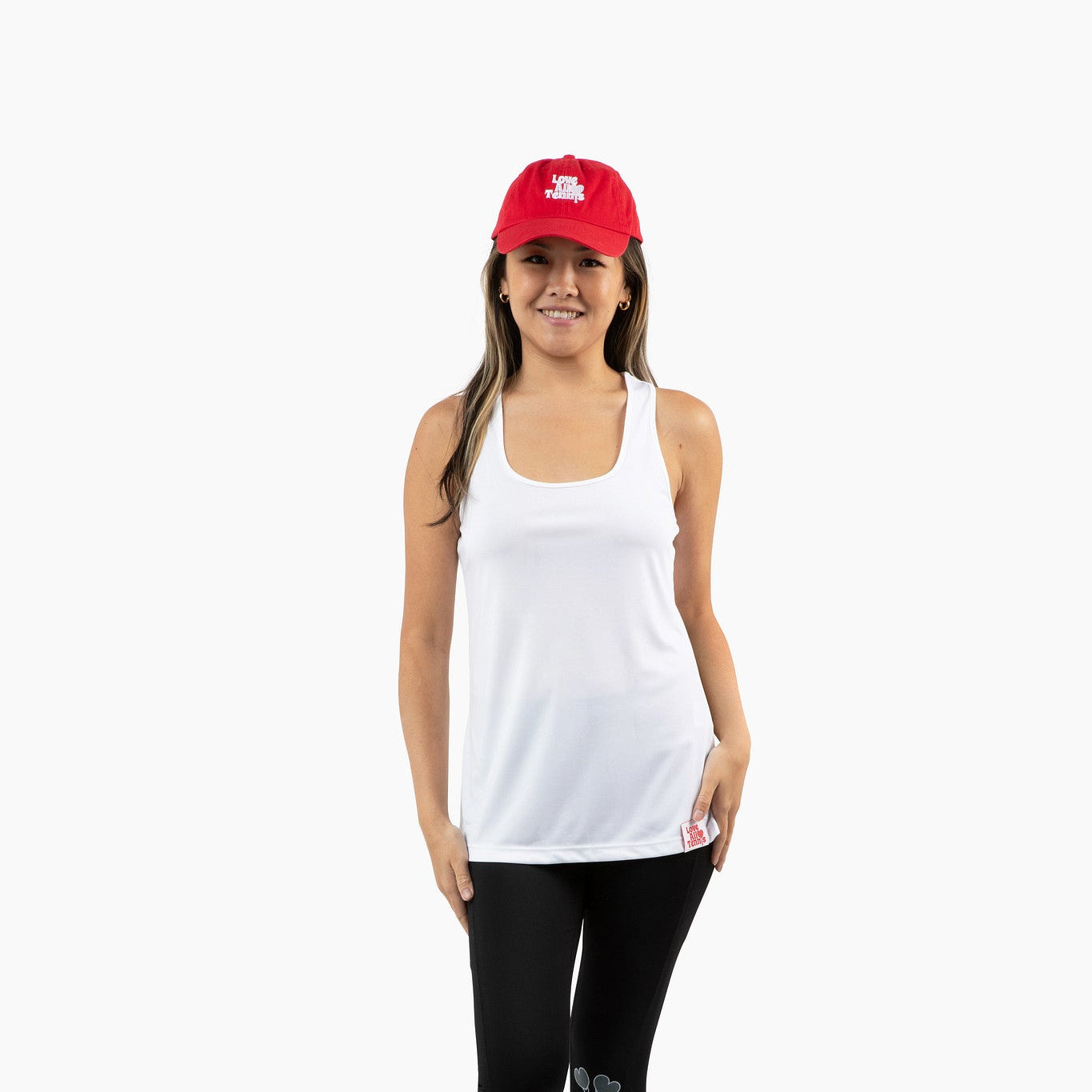 Woman wearing a white tank top, black leggings, and a red cap on a white background