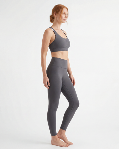 Woman wearing a gray sports bra and leggings on a white background