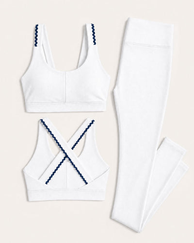 White sports bra and leggings set with navy accents on a beige background