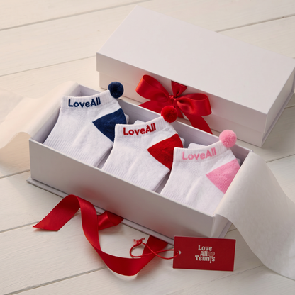 Box of socks with 'LoveAll' branding on a light wooden surface