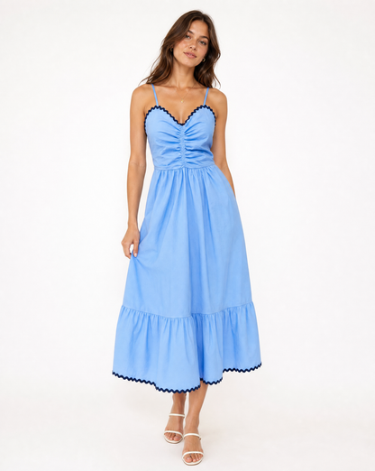 Woman in blue and navy thin strapped dress on white background