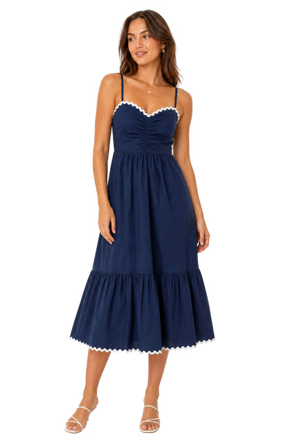 Woman wearing a navy blue dress with white trim on a white background