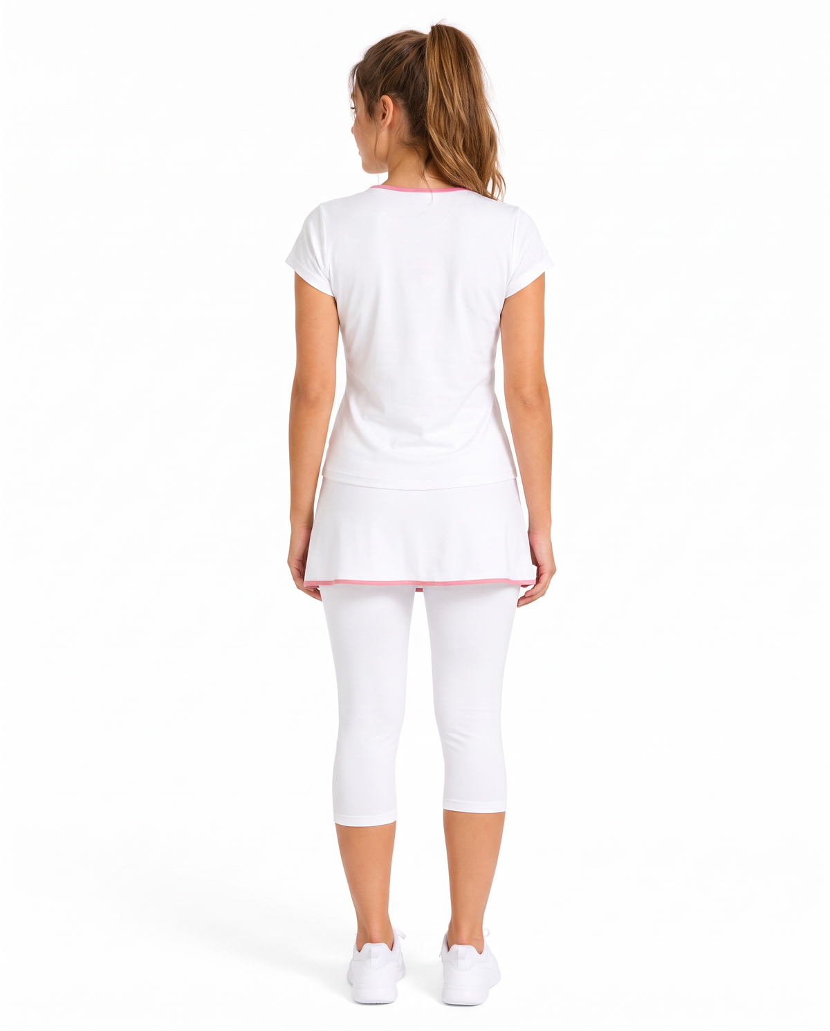A woman viewed from the back wearing a white short-sleeve athletic top with pink trim, matching white capri leggings, and white sneakers against a plain white studio background.
