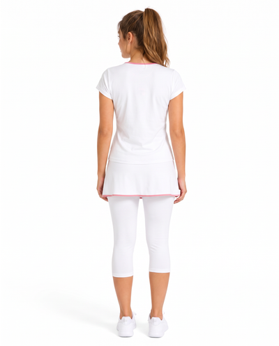 A woman viewed from the back wearing a white short-sleeve athletic top with pink trim, matching white capri leggings, and white sneakers against a plain white studio background.