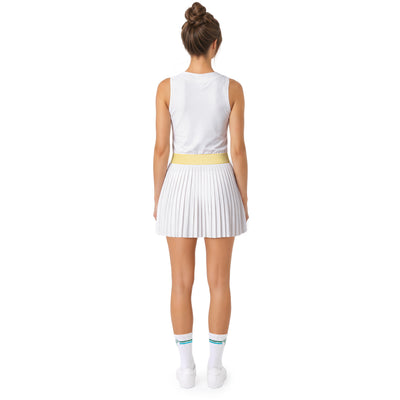 A woman shown from the back wearing a sleeveless white athletic top and a pleated white tennis skirt with a yellow waistband, standing against a plain white background.