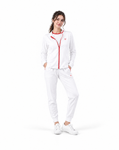 A woman modeling a white athletic tracksuit with red trim and a red front zipper, paired with white sneakers, on a solid white background.