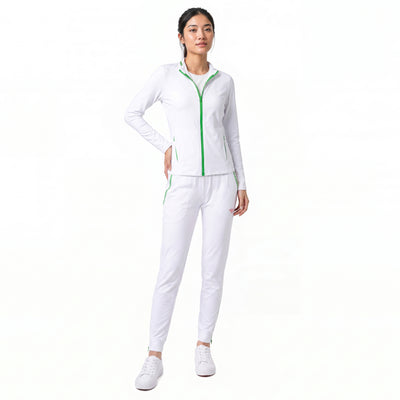 A woman modeling a white athletic tracksuit with bright green zipper and piping details, paired with white sneakers, against a solid white background.