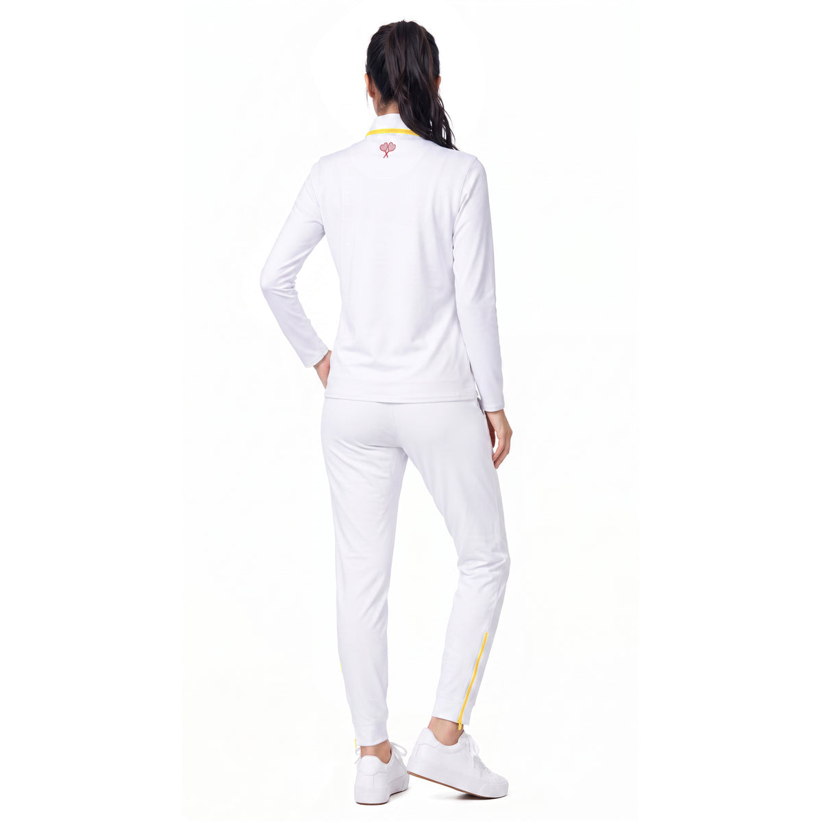 A woman shown from the back wearing a white athletic tracksuit with a long-sleeve top and matching jogger pants, featuring small yellow and red accents on the collar and leg.