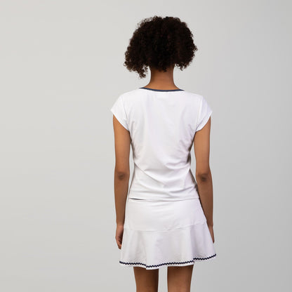 Person wearing a white tennis skort and top with a skirt on a plain background