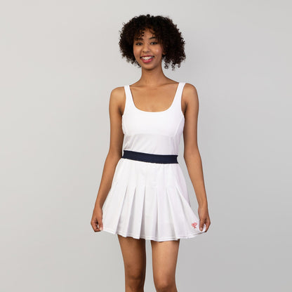 Woman wearing a white dress with a navy belt on a gray background