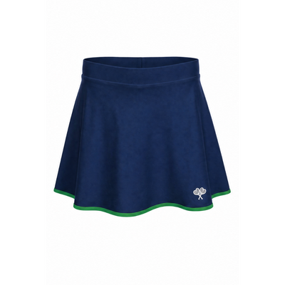 A navy blue athletic skort with a thin green trim along the hem and a small white embroidered clover logo on the lower left side, shown against a plain white background.