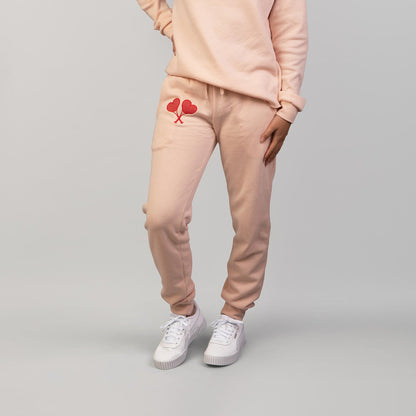 Person wearing a matching peach sweatshirt and pants set with heart designs on a gray background