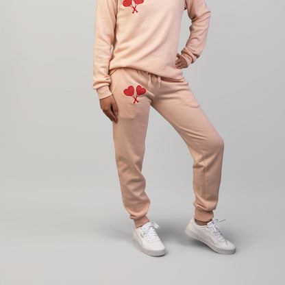 Woman wearing a peach sweatsuit set with red heart designs on a gray background
