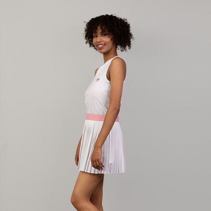 Woman wearing a white pleated dress with a pink waistband on a gray background